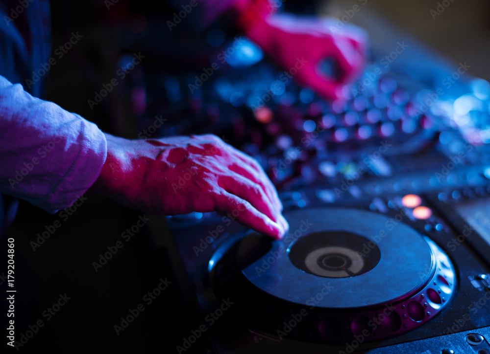 Dj playing music at sound mixer in night club