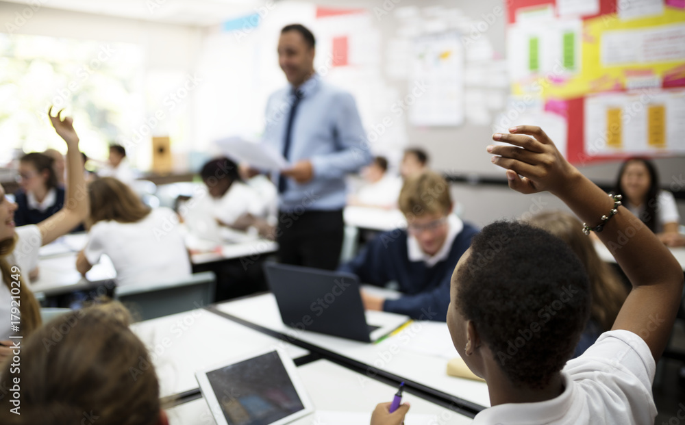 Students with their hands up responding to their teacher