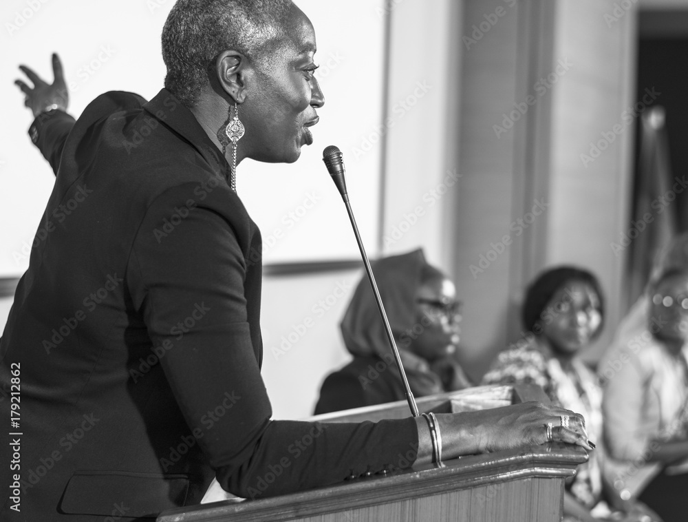 A Middle Age African Descent Woman Speaking into a Microphone