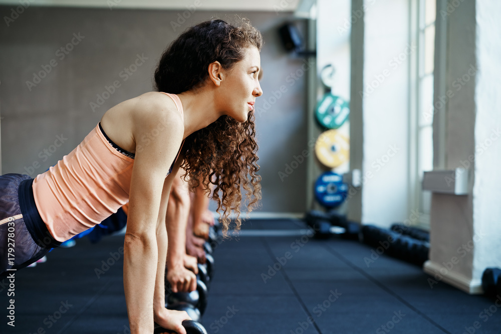 Focused woman doing pushups on weights in a gym class