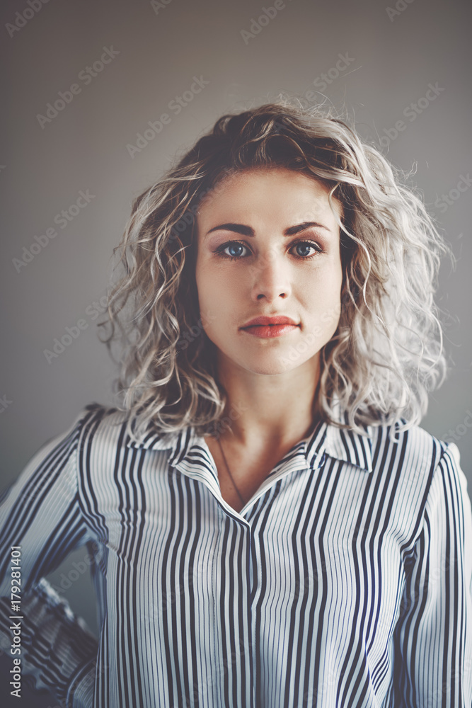 Focused young businesswoman standing alone in an office