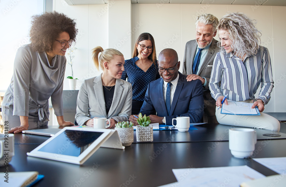 Smiling colleagues working together at a table in an office