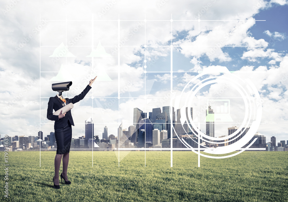 Camera headed woman standing on green grass against modern citys