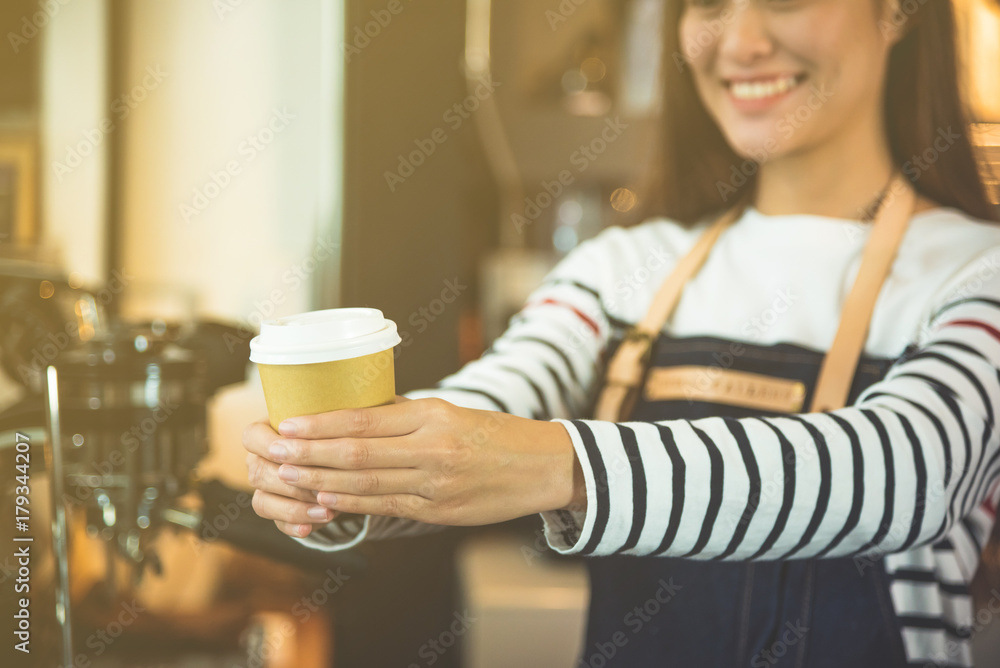 快乐的咖啡师带着美丽的微笑为顾客端上一杯咖啡