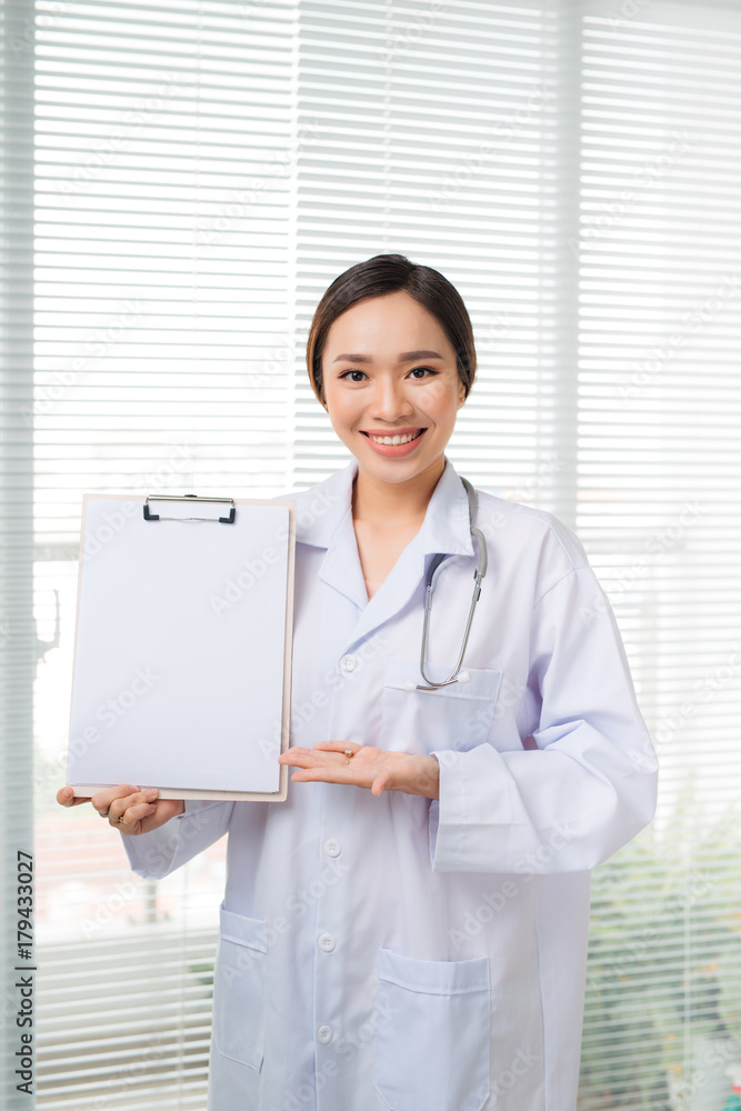 Asian young female doctor upset point to blank clipboard while  standing at hospital