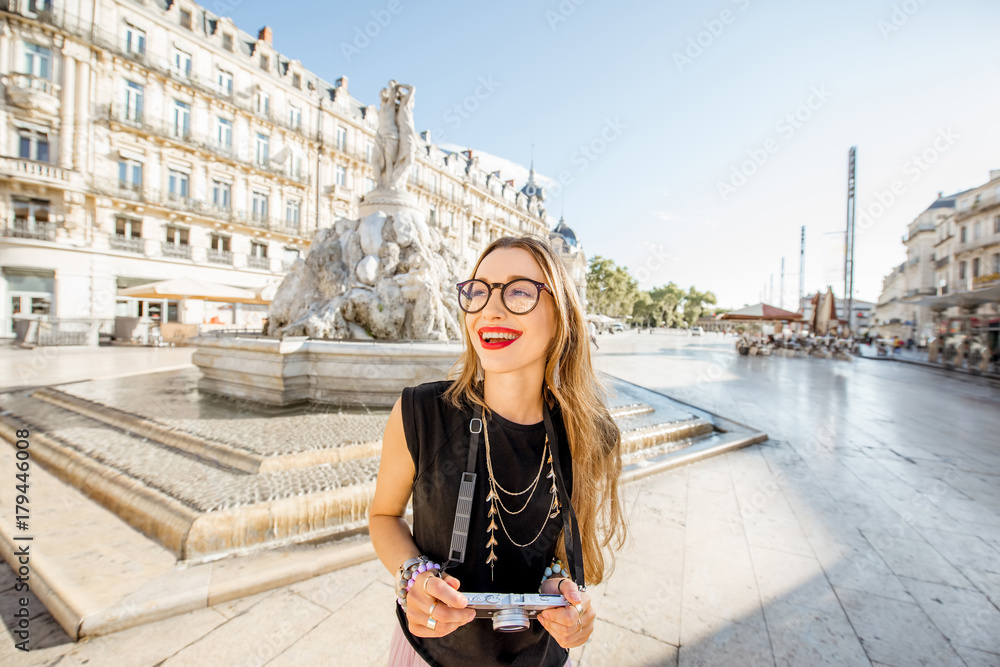 Young woman tourist standing with photo camera on the Comedy square with main fountain on the backgr