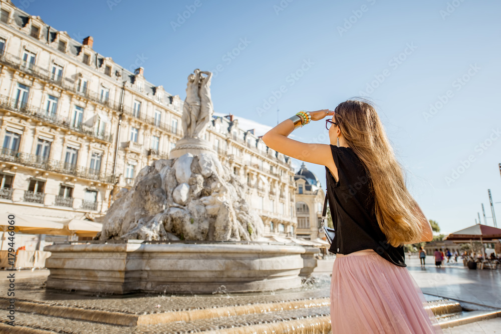 Young woman tourist standing with photo camera on the Comedy square with main fountain on the backgr