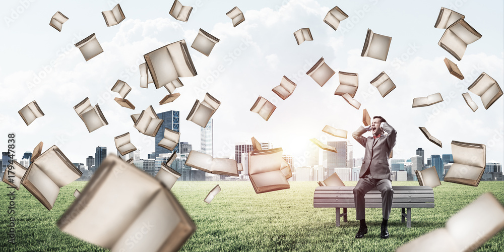 Many old books falling from above and student guy sitting on ben