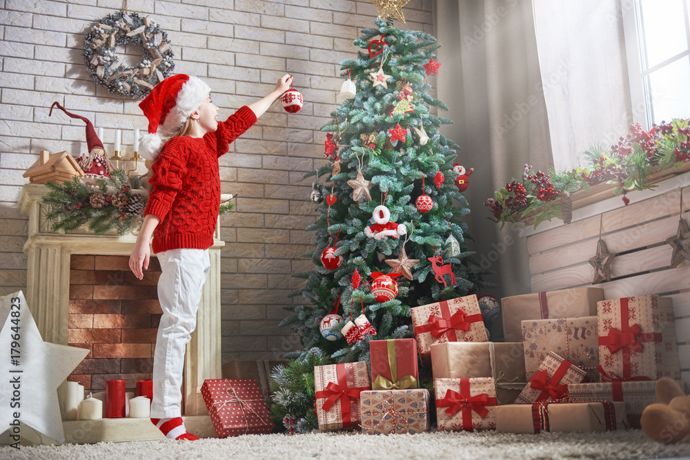 girl is decorating Christmas tree