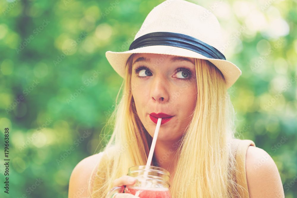 Young woman drinking a smoothie outside on a beautiful summer day