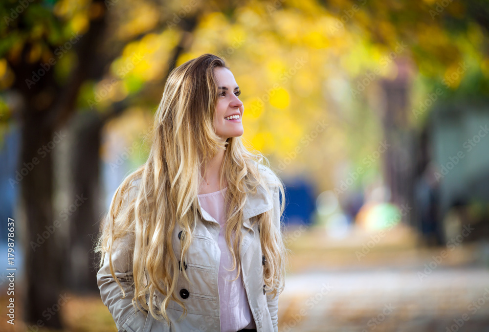 Smiling woman under colorful autumn trees walking in the city