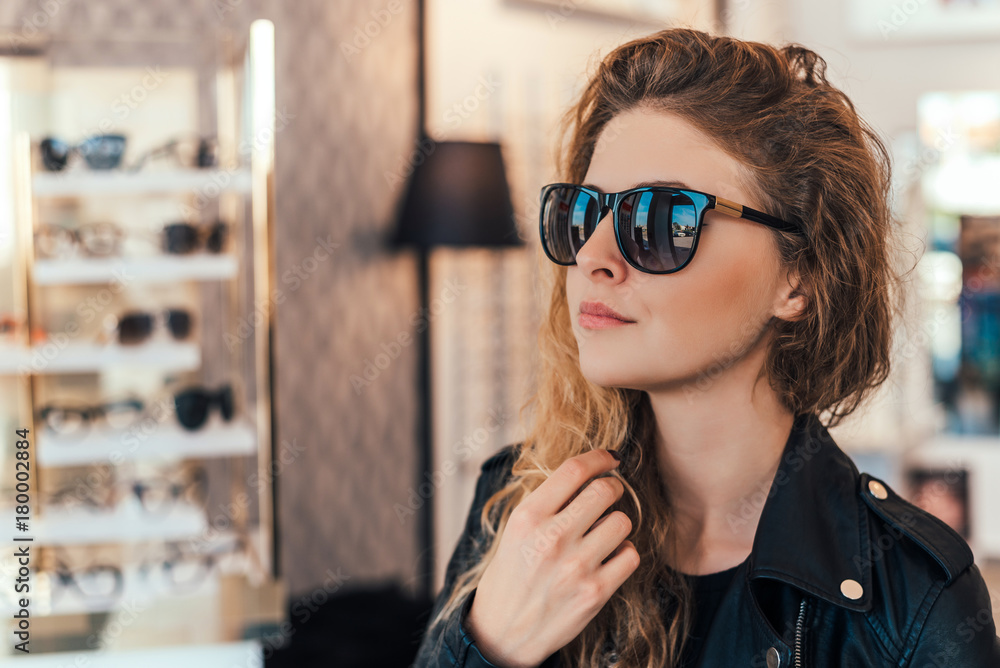 Happy woman buying sunglasses in shop.