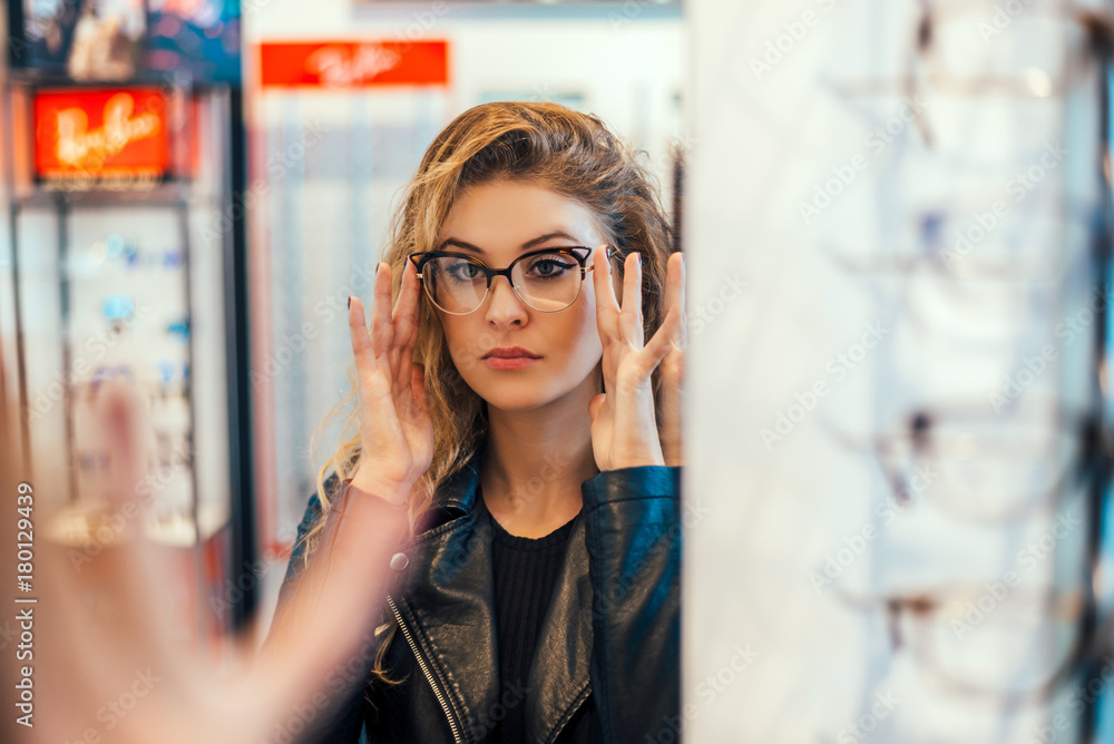 一名年轻女子在眼镜店试戴眼镜。