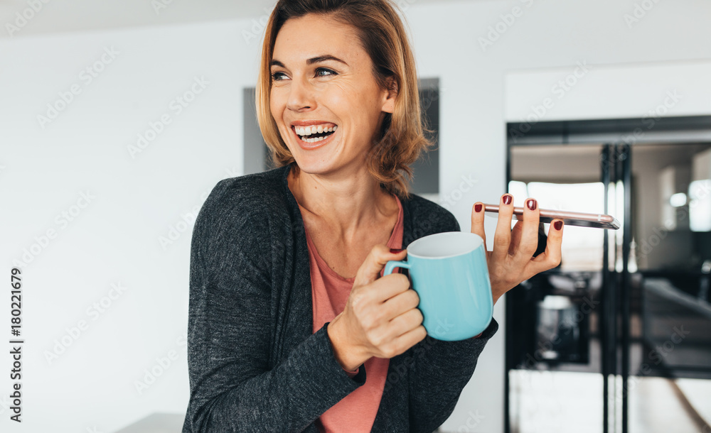 Woman holding mobile phone and coffee mug