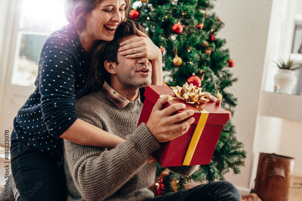 Young couple having fun celebrating Christmas with gifts.