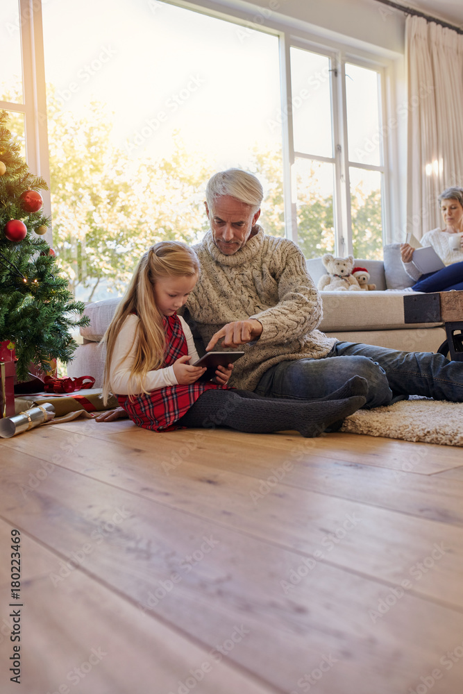 Little girl and grandfather with digital tablet at home