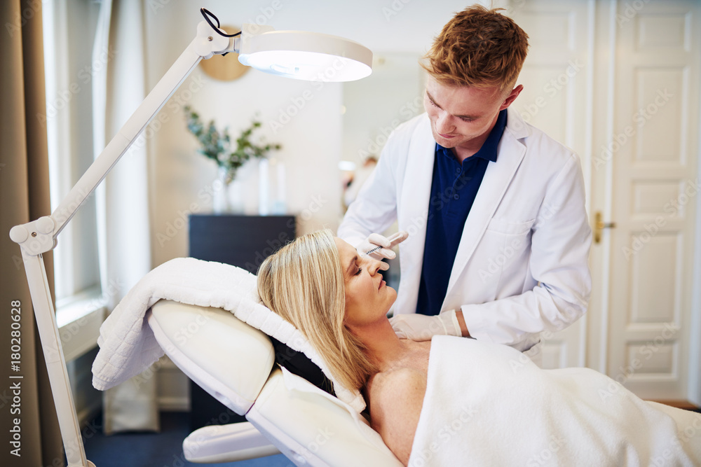 Doctor injecting botox around the eyes of a mature client