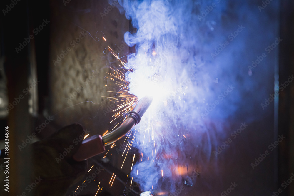 A man with a welding mask welding something together