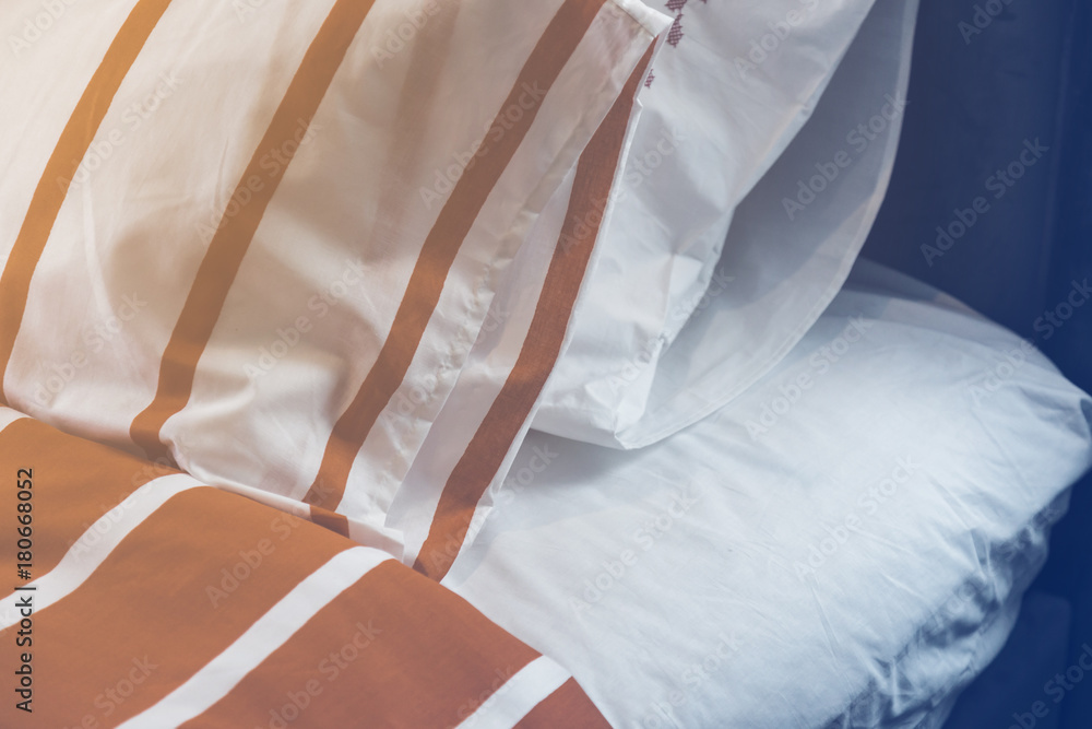 Bed maid-up with clean white pillows and bed sheets in beauty room. Close-up. Lens flair in sunlight