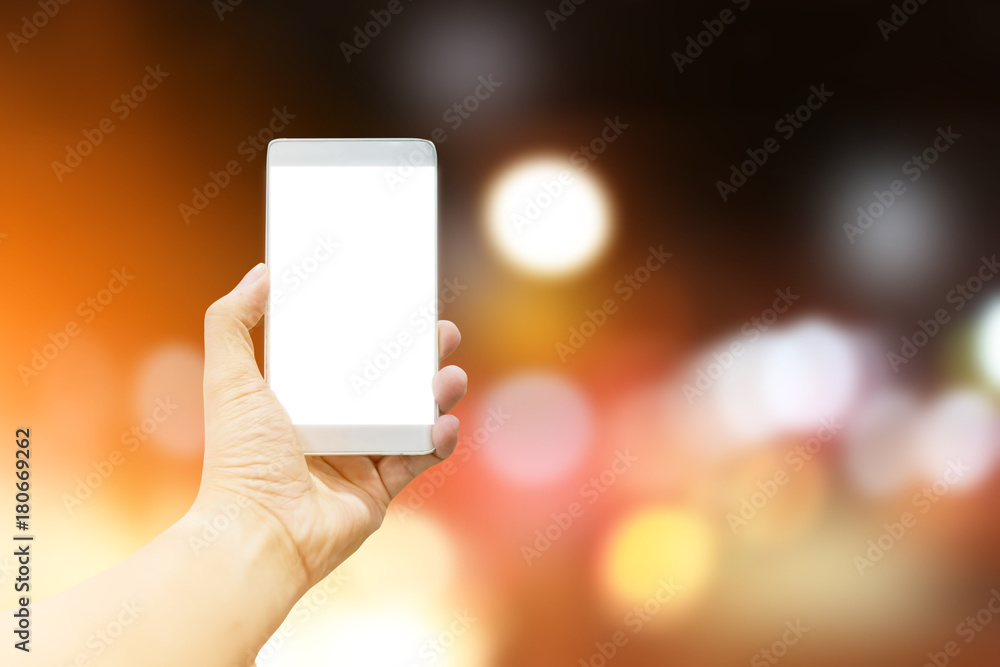 Man hand holding the white smartphone on GOLDEN light bokeh background.