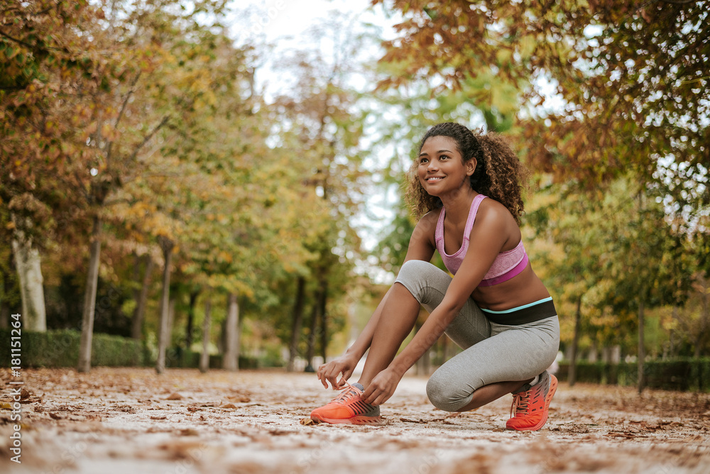 Woman tying shoes laces before running, getting ready for jogging in park.