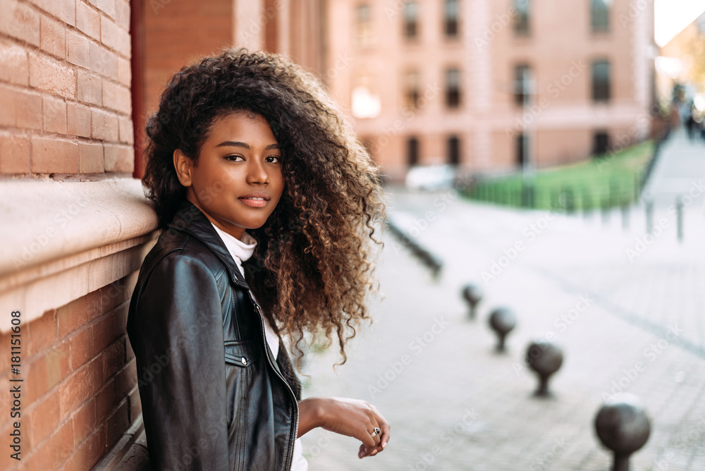 Portrait of beautiful woman wearing a black leather jacket against the wall.