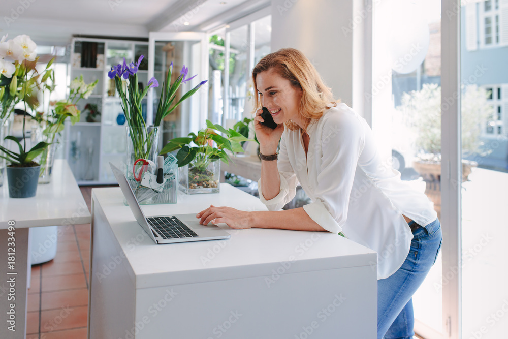 Florist talking on mobile phone and using laptop