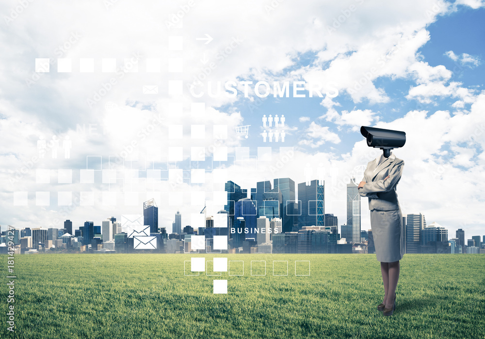 Camera headed woman standing on green grass against modern citys