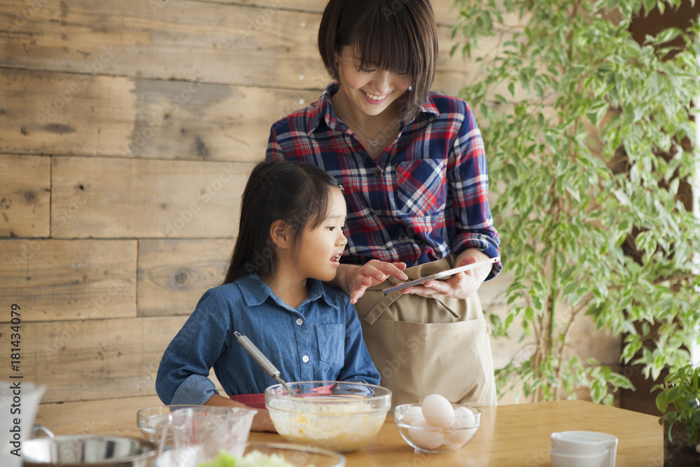 可爱的小女孩和她美丽的妈妈。他们在家的厨房里做饭时面带微笑。