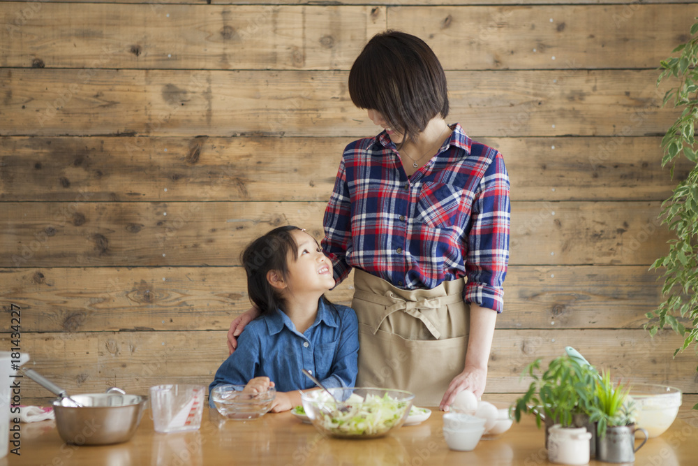 可爱的小女孩和她美丽的妈妈。他们在家的厨房里做饭时面带微笑。