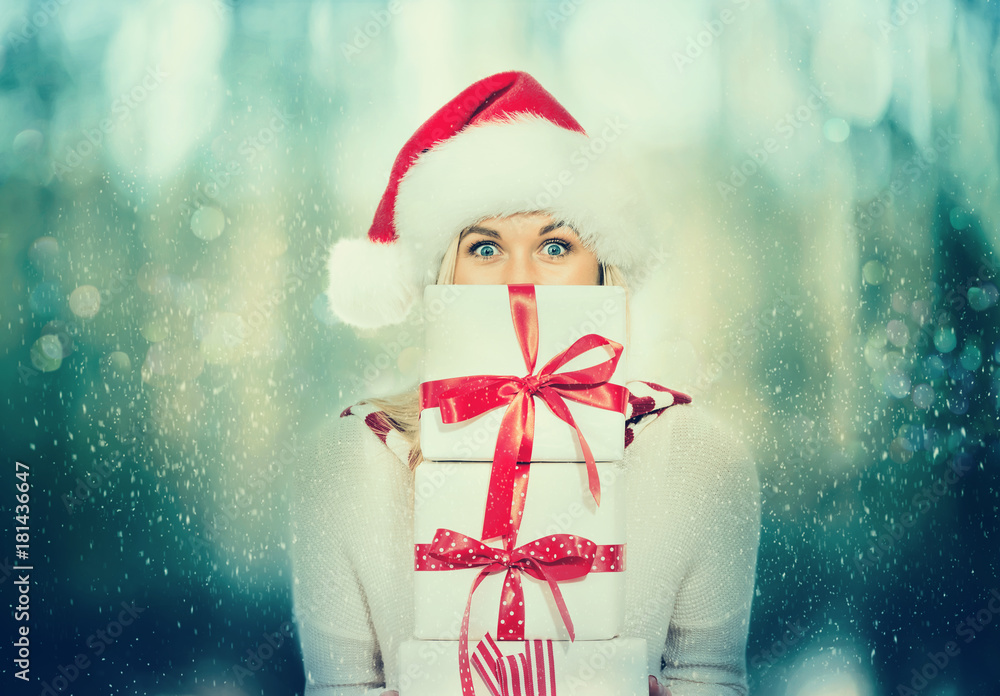 Happy young woman holding present boxes in snowy night