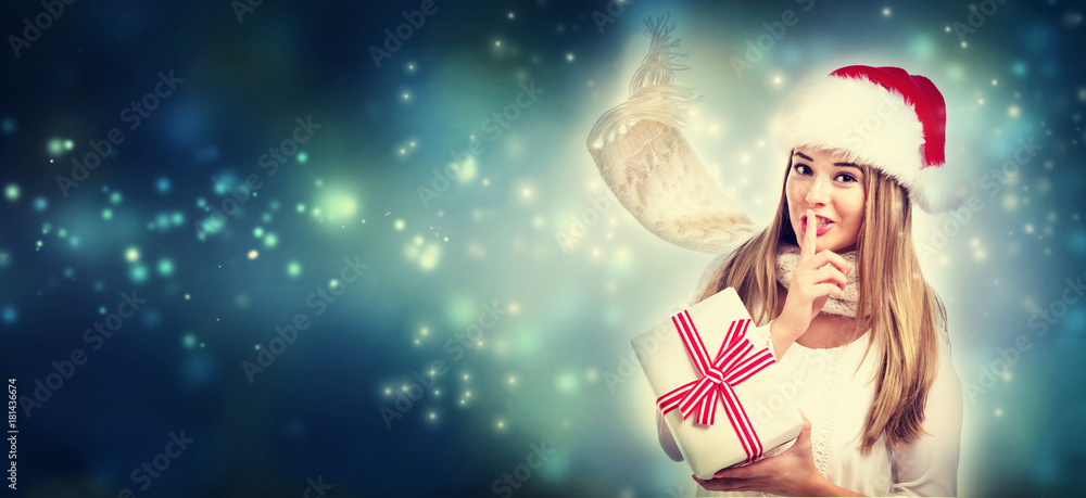 Happy young woman holding a present box in snowy night