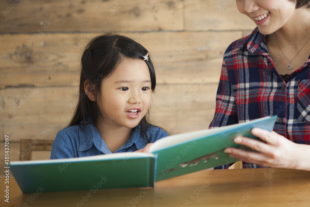 A young mother and a girl read a picture book together.