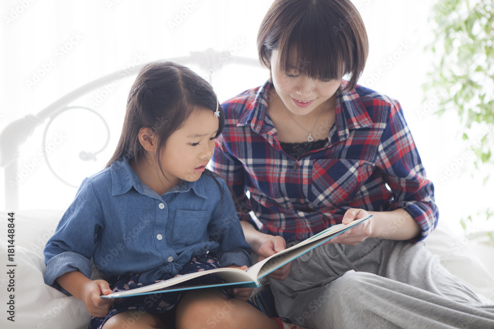 A young mother and a girl read a picture book together.