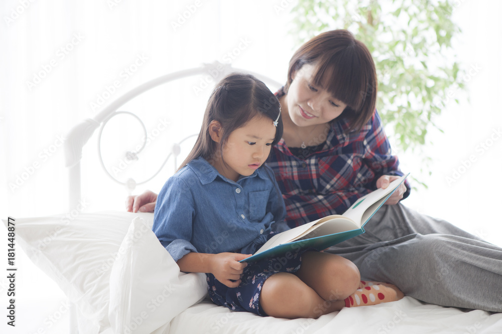 A young mother and a girl read a picture book together.