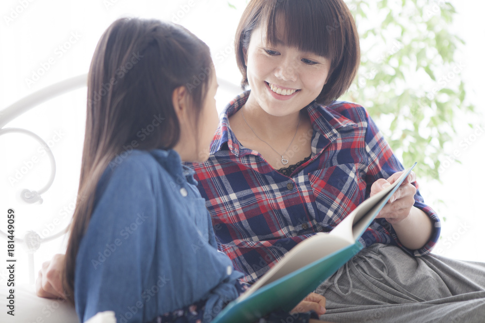 一位年轻的母亲和一个女孩一起读了一本图画书。