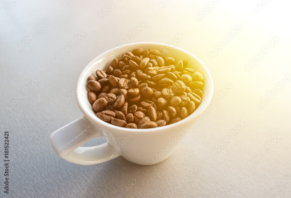 White cup with coffee beans on gray woden background