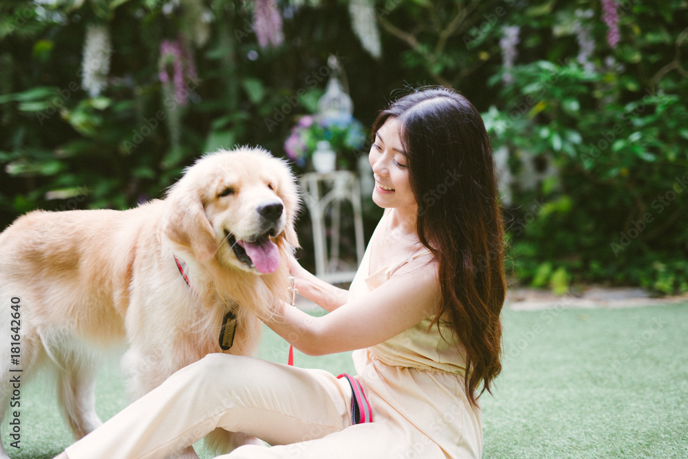 带着狗金毛寻回犬的女人在公园里的肖像，日落在门外