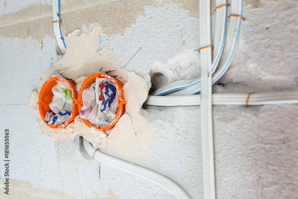 New electrical installation, socket plastic boxes and electrical cables on the wall