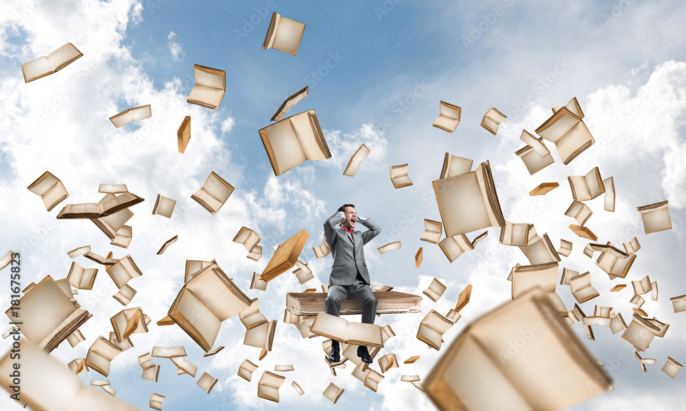 Young man on pile of books dont want to hear anything