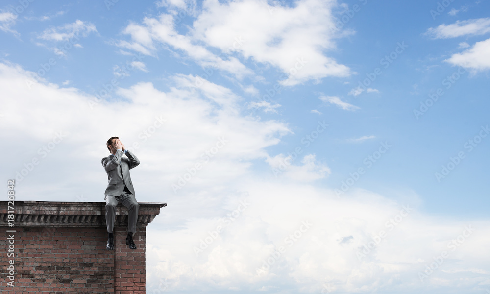 Young man on building edge do not want to see anything