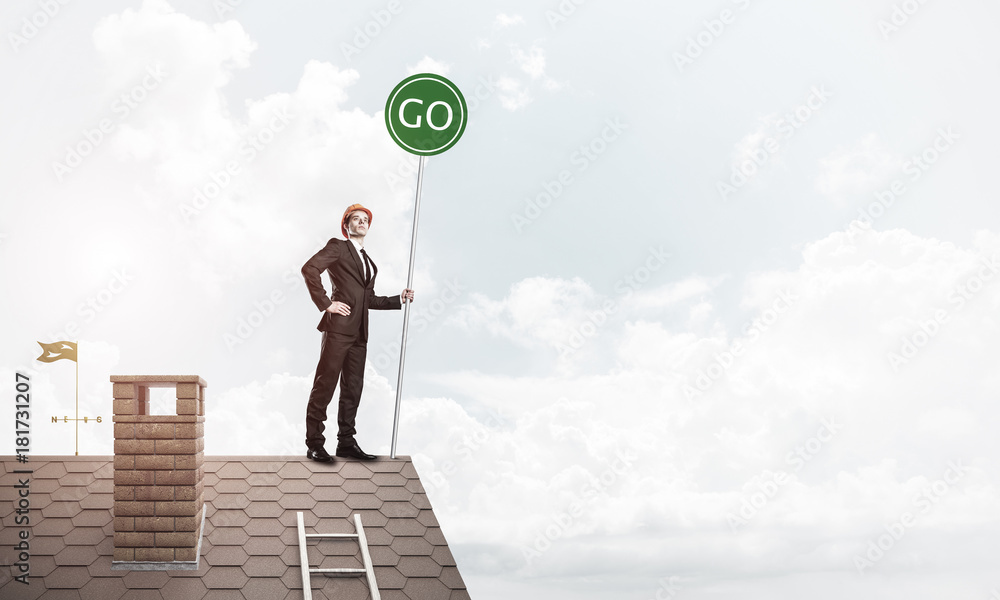 Businessman in suit on house top with ecology concept signboard.