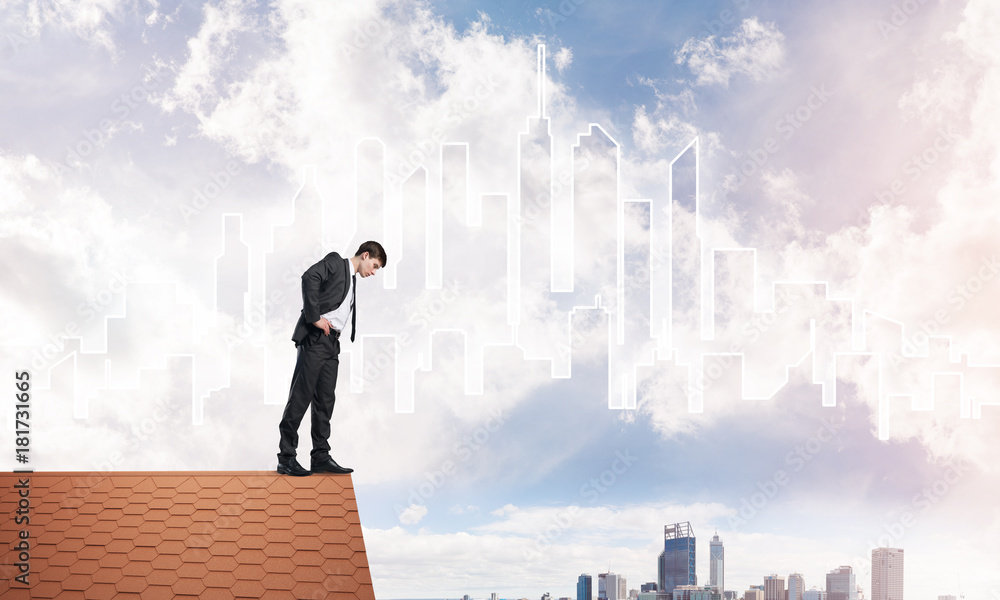 Businessman looking down from roof and modern cityscape at background. Mixed media