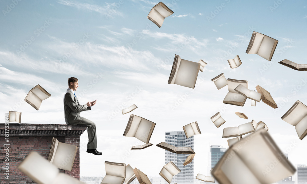 Man using smartphone and many books flying in air