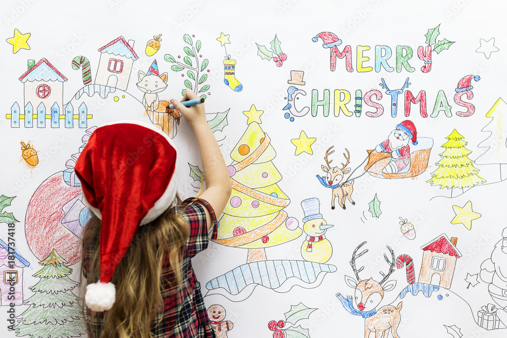 Little girl drawing Christmas pictures on a white wall