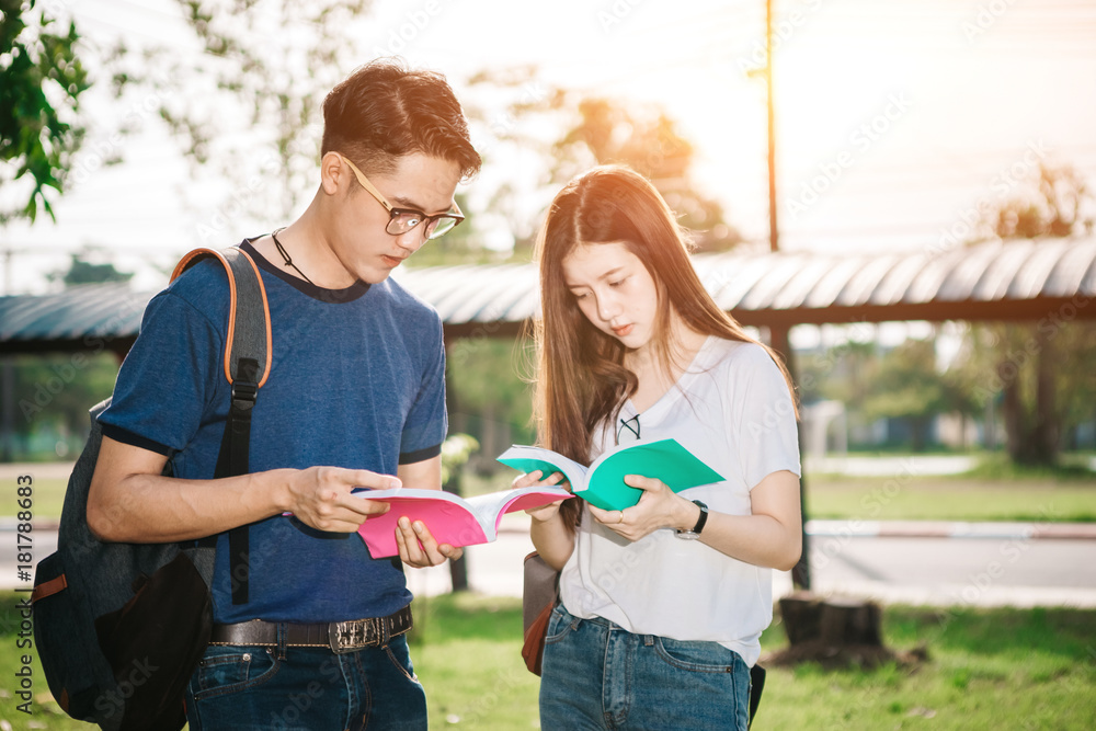 一群年轻或十几岁的亚洲学生在大学里微笑着读着书，看着ta