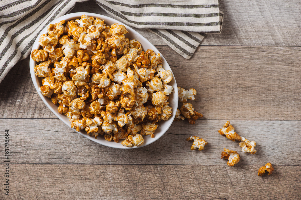 Caramel opcorn in bowl on the wooden table.