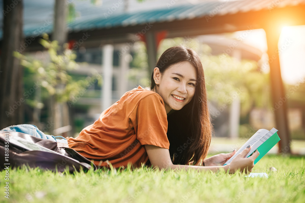 一个年轻或十几岁的亚洲女学生在大学里微笑着看书，看着平板电脑