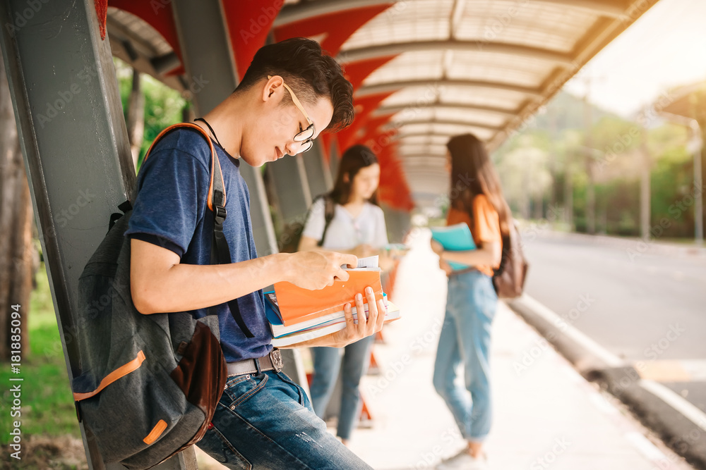 一群年轻或十几岁的亚洲学生在大学里微笑着读着书，看着ta