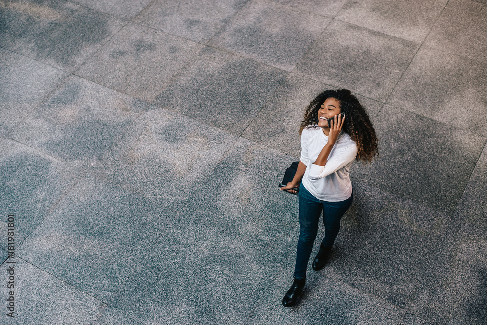 带着行李的年轻女游客边走边打电话，俯视图。